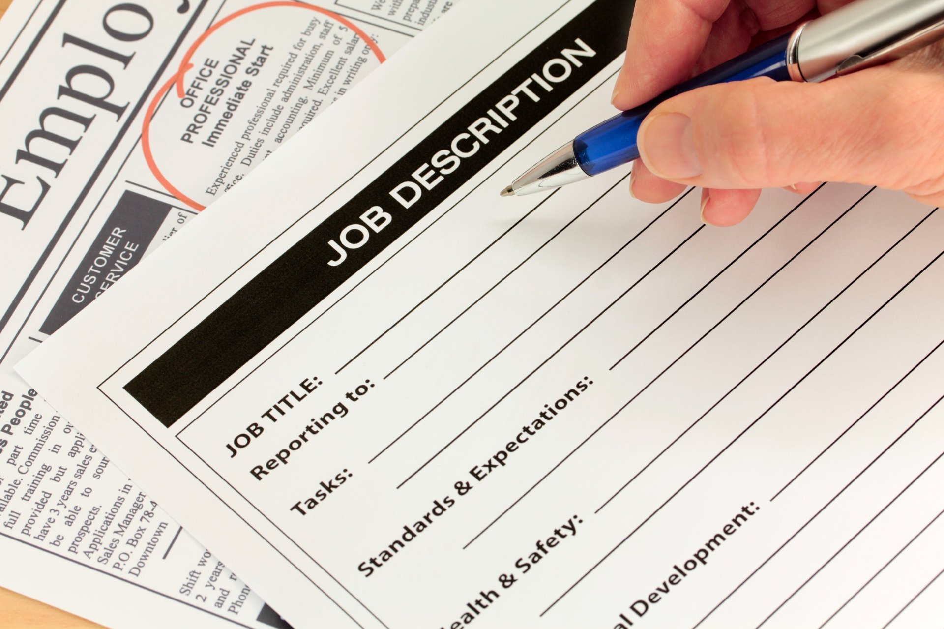 Job Description with Hand and Pen and Newspaper Ad