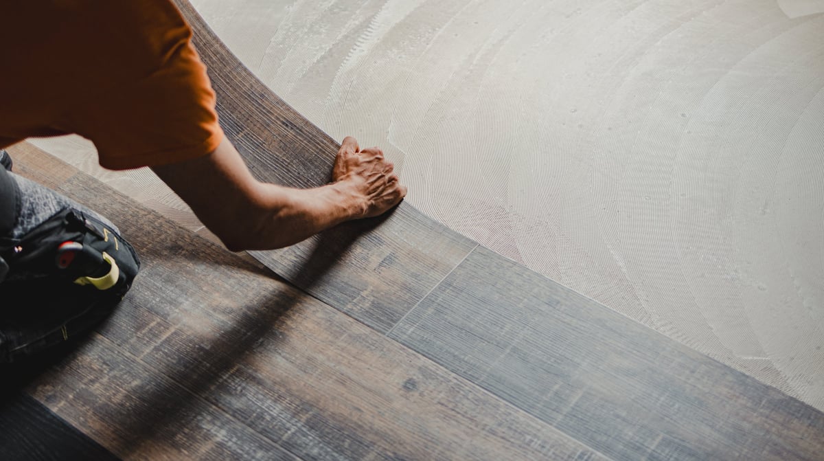 Construction worker installing luxury vinyl plank flooring