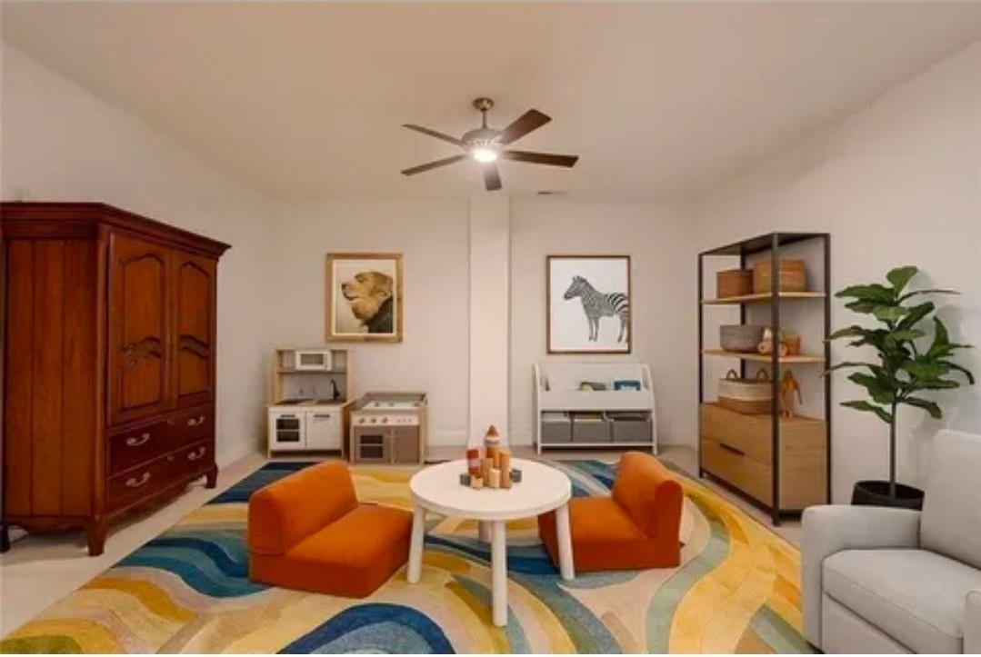 Modern living room with two orange accent chairs, white round table, colorful area rug, ceiling fan, wooden furniture pieces, and potted plant